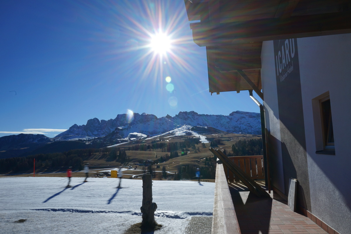 Hotel, Skipiste mit Skifahrern, blauer Himmel und Sonnenschein